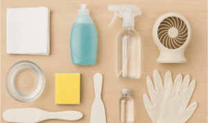 Flat lay of cleaning supplies including gloves, spray bottle, sponge, and detergent.